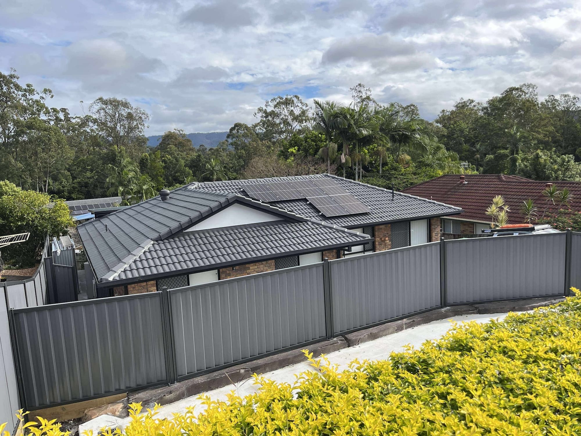 A custom boundary fence being installed on a sloped property in the Gold Coast.